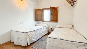 Un dormitorio con dos camas individuales, una puerta de madera, una ventana y una lámpara.
