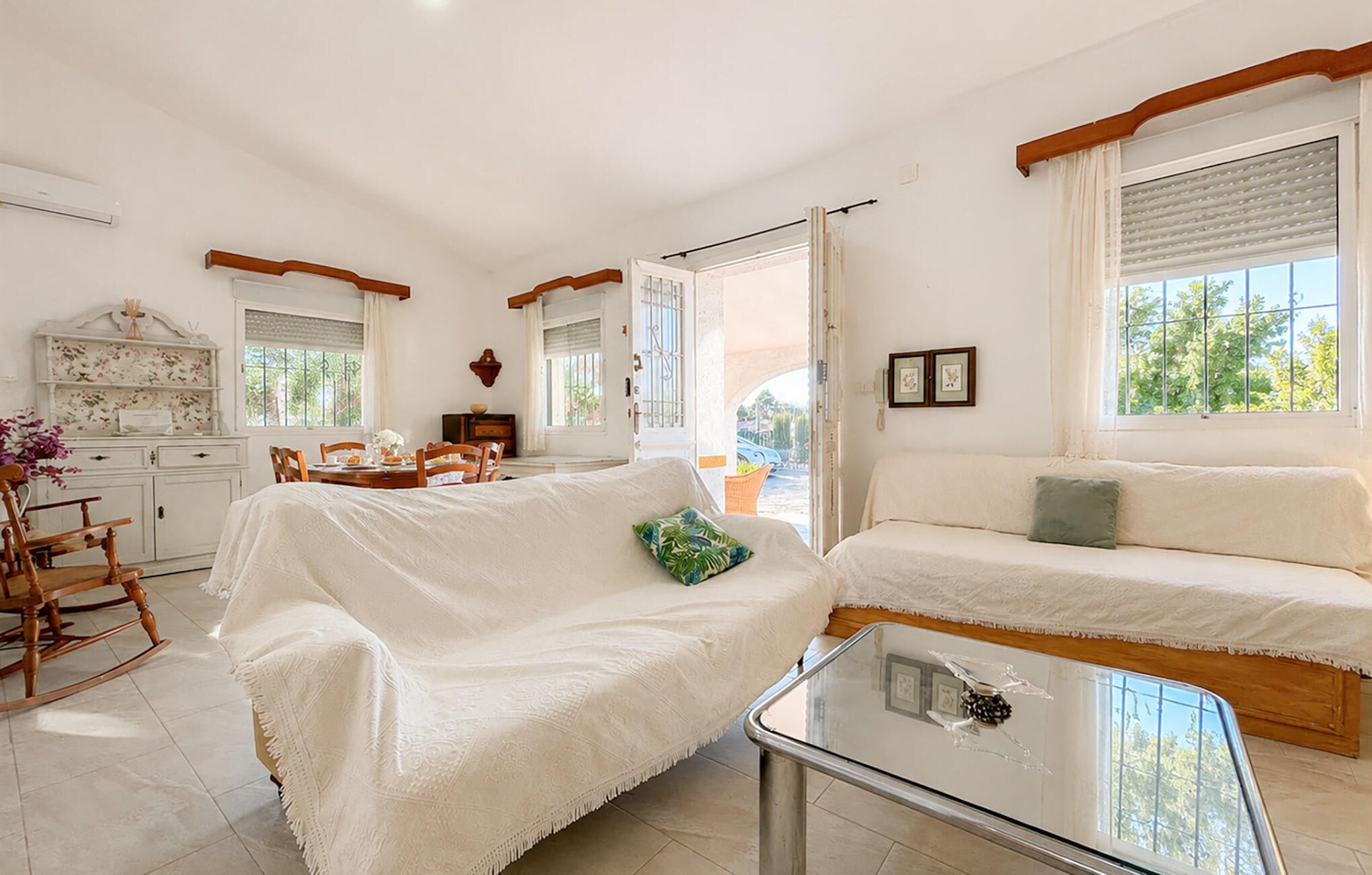 A cozy living room with a sofa, a dining table, and a glass coffee table.