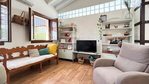 A cozy living room with a wooden bench, a sofa, and a television on a stand.