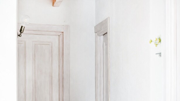 Une porte blanche avec un interrupteur et un luminaire fixé au mur.