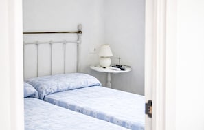 A bedroom with a bed, a bedside table with a lamp, and a radiator.