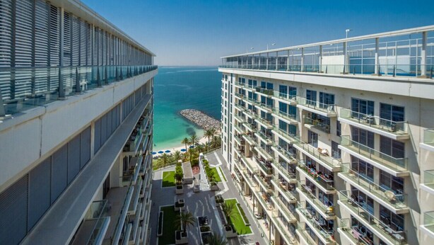 Un hotel di grandi dimensioni con numerosi balconi affacciato su una spiaggia e il mare.