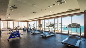 Una palestra con tapis roulant, ellittiche e una cyclette, ampie finestre con vista sul mare.