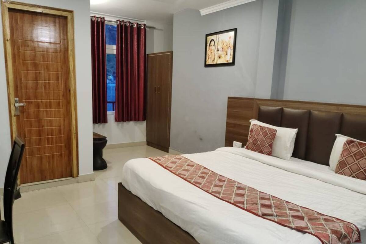 Een slaapkamer met een groot bed, een houten deur, een kledingkast en een lijst met een afbeelding aan de muur.