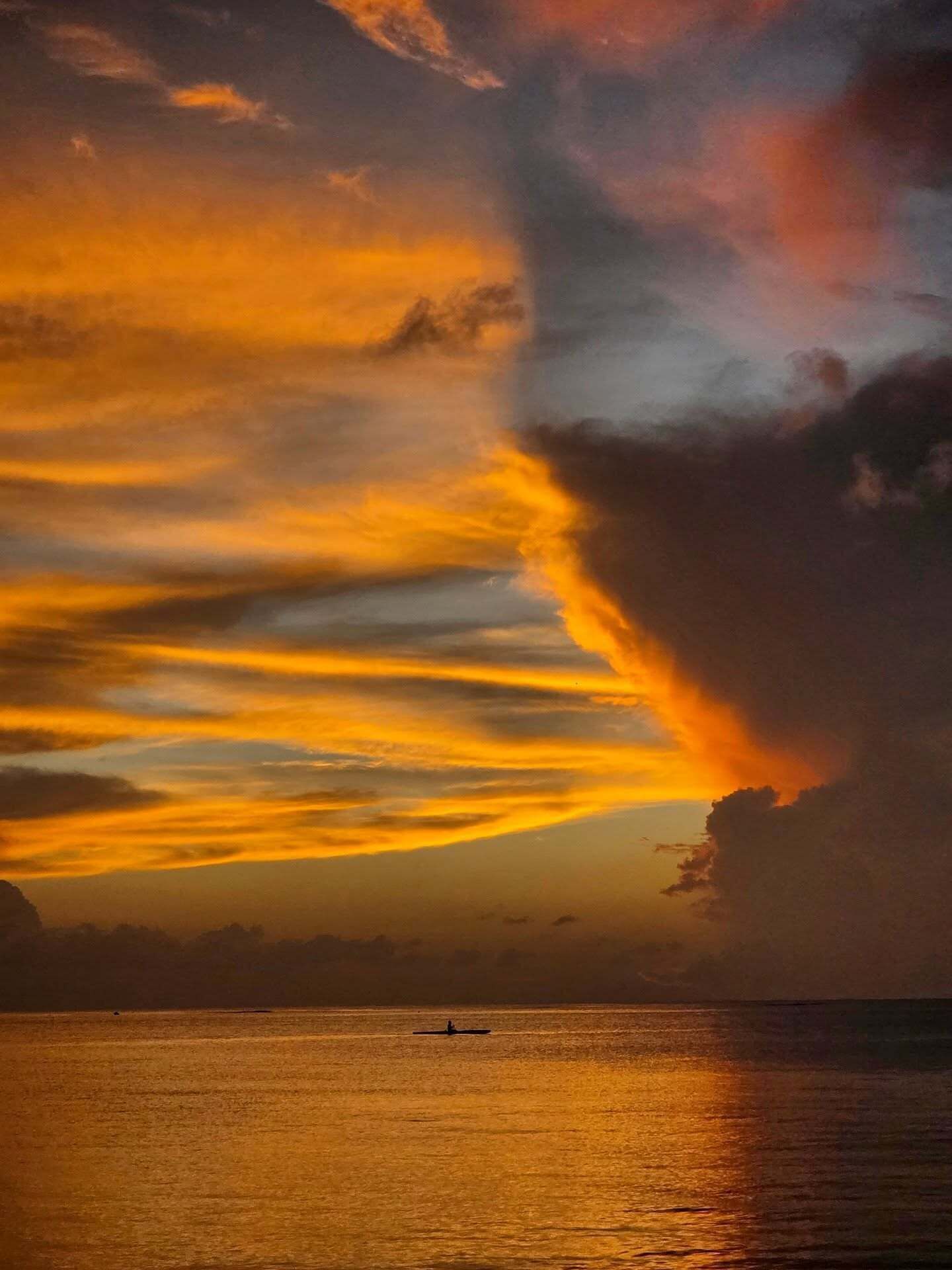 Ein Sonnenuntergang über einem ruhigen Meer mit einem Boot in der Ferne.