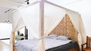 A wooden four-poster bed with a grey and black bedspread, a wooden headboard, and a white canopy. - Cozy & Safe Island Studio Suite (Garapan)