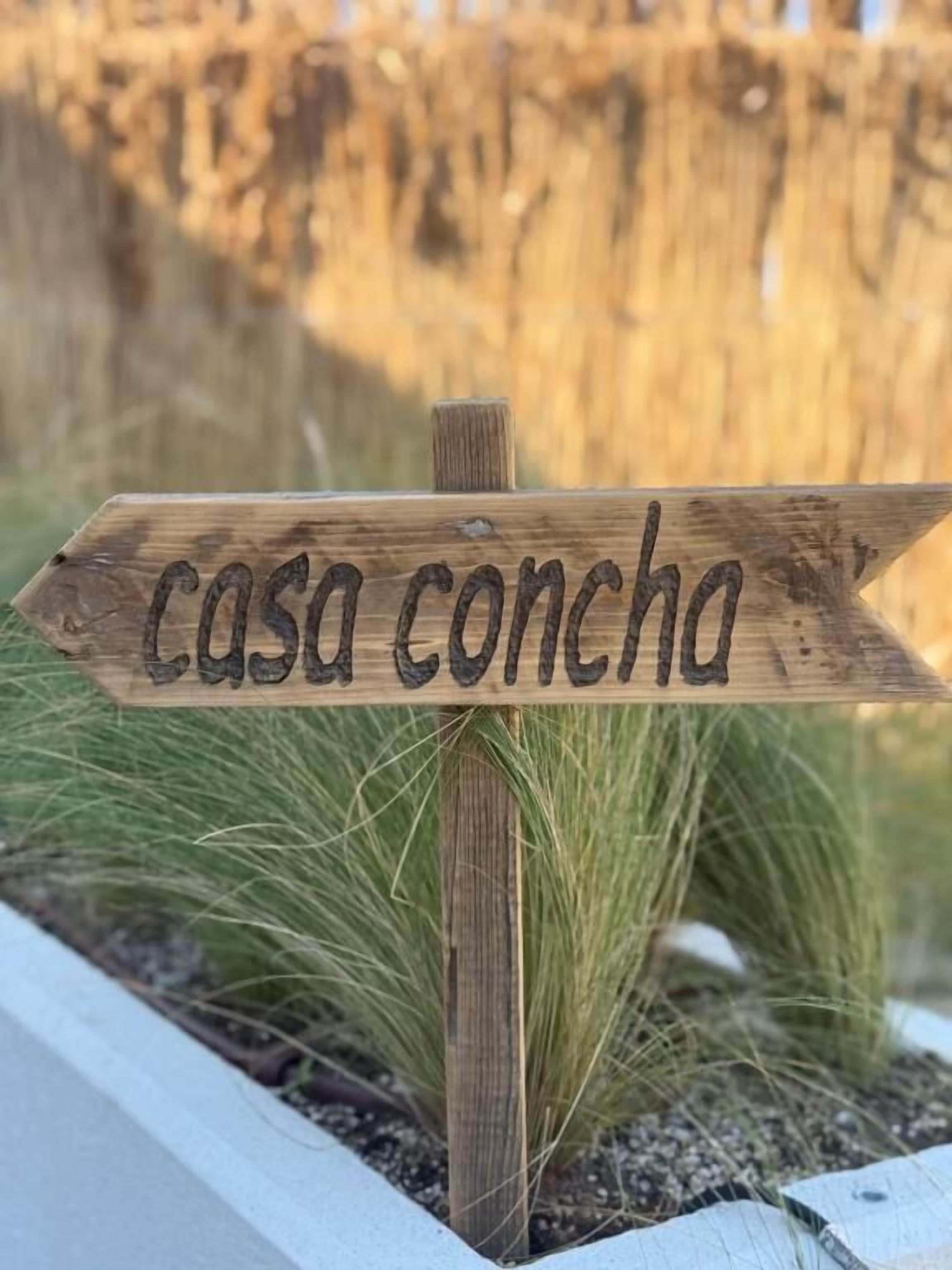 Uma placa de madeira com o texto 'casa concha' apontando para a direita.