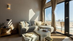 A modern living room with a sofa, coffee table, and a view of the beach through large windows. - OASIS VILLAGE (Eforie Nord)