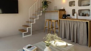 A modern living space with a staircase, a flat-screen TV, a coffee table with books and a vase, and a wall-mounted shelf with decorative items. - OASIS VILLAGE (Eforie Nord)