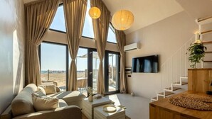 A modern living room with a sofa, coffee table, and a view of the beach. - OASIS VILLAGE (Eforie Nord)