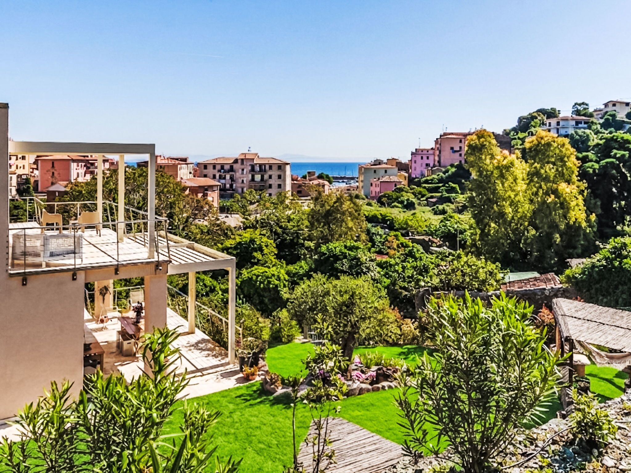 Zona residencial con un edificio moderno que cuenta con un balcón, abundante vegetación y vista al mar.