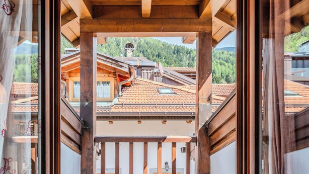 Een houten balkon met uitzicht op traditionele gebouwen en een berg op de achtergrond.