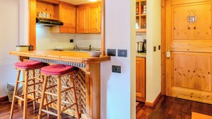 Een keuken met houten kasten, een bar met krukken en een houten deur met een hartvormige decoratie.