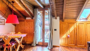 Een houten interieur met een eettafel, stoelen, een rode lamp en een schuifdeur naar een buitenruimte.