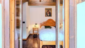 Een slaapkamer met een houten bed, een nachtkastje, een lamp en een religieus schilderij aan de muur.