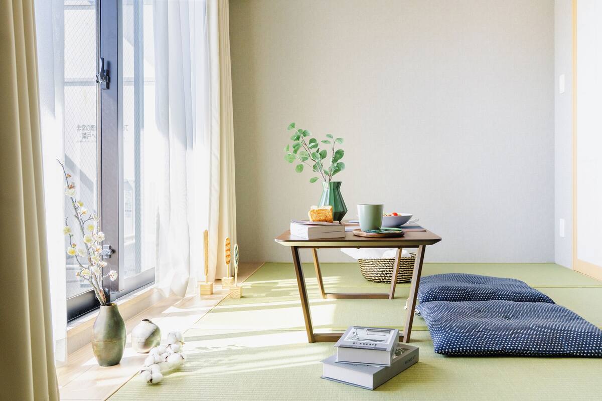 A room with tatami flooring, a low table with a vase, books, and a bowl.