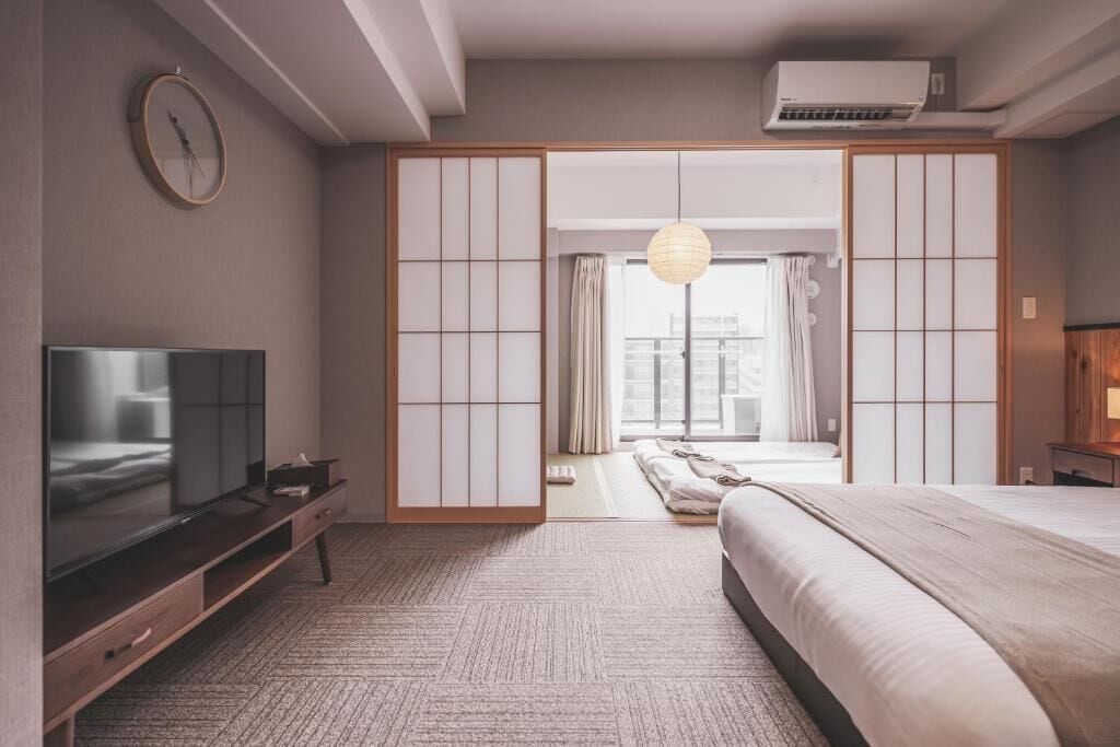 Una camera da letto moderna con TV, un letto, un armadio e vista sulla città.