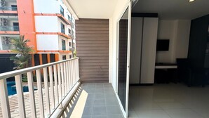 A balcony with a view of a building, a sliding glass door, and a tiled floor. - Cozy Pool-view Studio With Balcony - New Nordic VIP 3, Pratumnak (Pattaya)