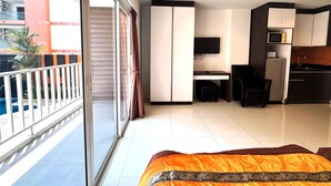 A modern hotel room with a balcony, a desk, a TV, a refrigerator, and a kitchen area. - Cozy Pool-view Studio With Balcony - New Nordic VIP 3, Pratumnak (Pattaya)