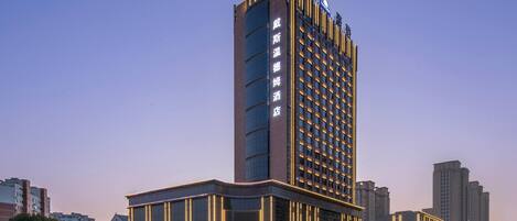 A high-rise hotel with a modern design, featuring a prominent entrance and a large digital sign displaying the hotel's name.