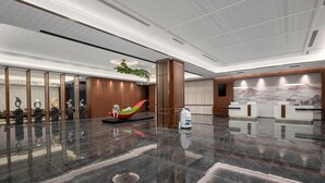 Un hall d’entrée moderne comprenant un comptoir d’accueil, une plante décorative et un espace détente aménagé avec un design original représentant un bateau rouge.