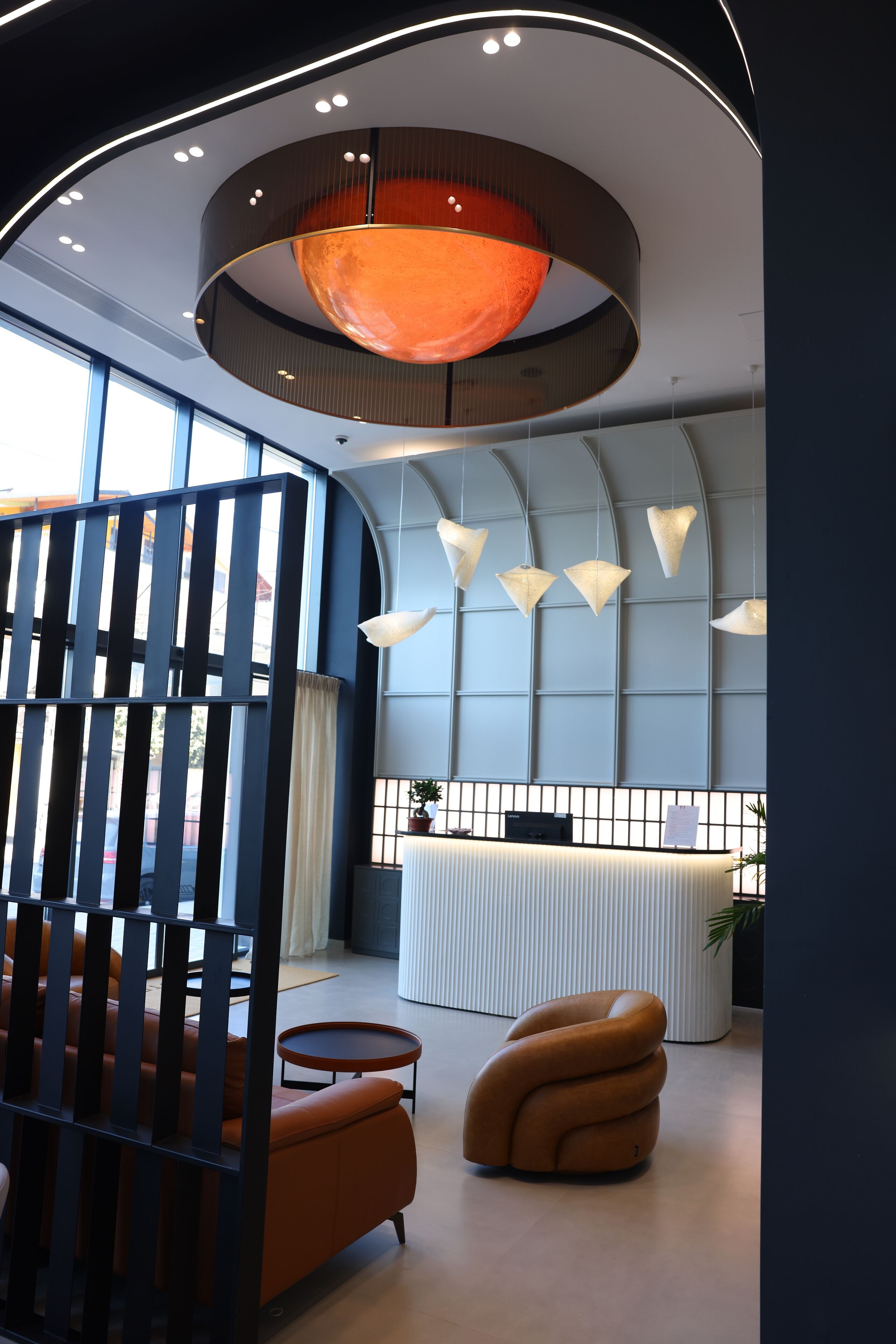 A modern reception area with a curved desk, a unique seating arrangement, and a distinctive ceiling light fixture.