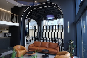 A modern lobby with a leather sofa, round tables, and a high ceiling with unique lighting. - Mece Hotel (Tirana)