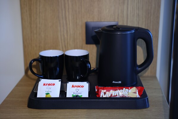 Una cafetera, dos tazas y dos bolsitas de té Kraco sobre una bandeja.