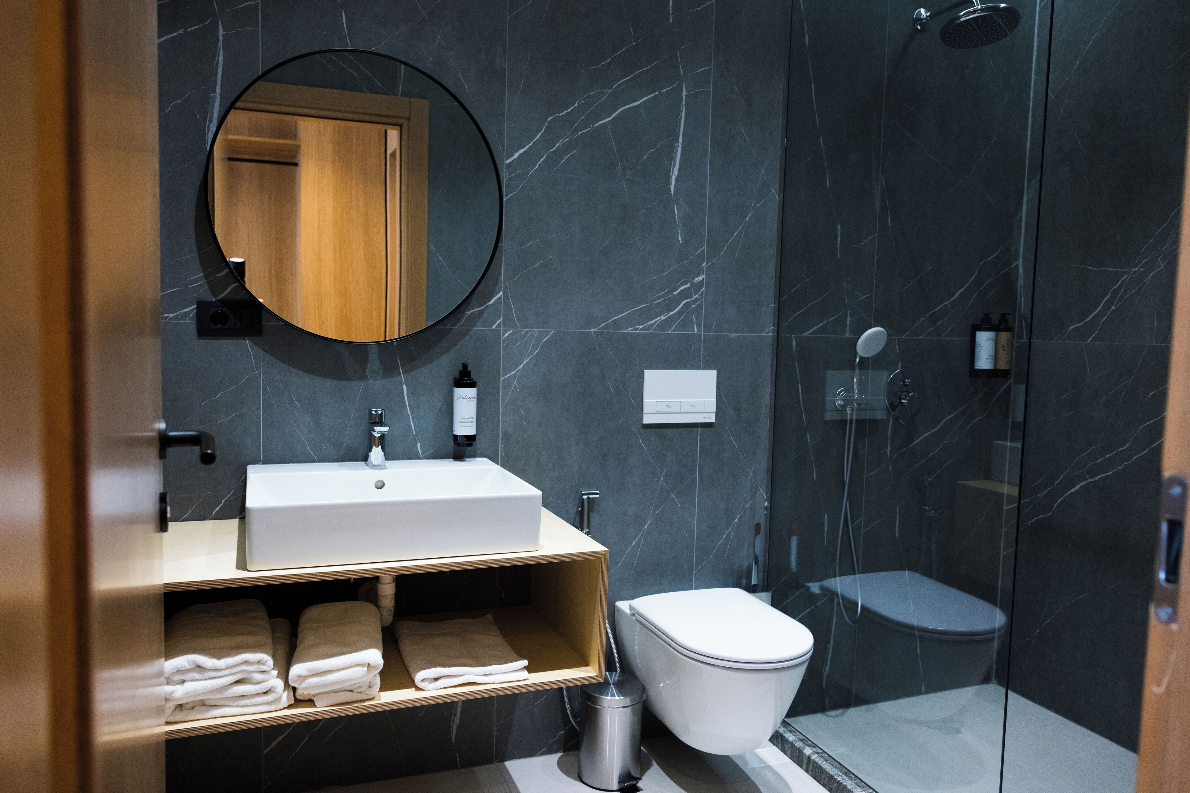 A modern bathroom with a marble sink, a toilet, and a shower.