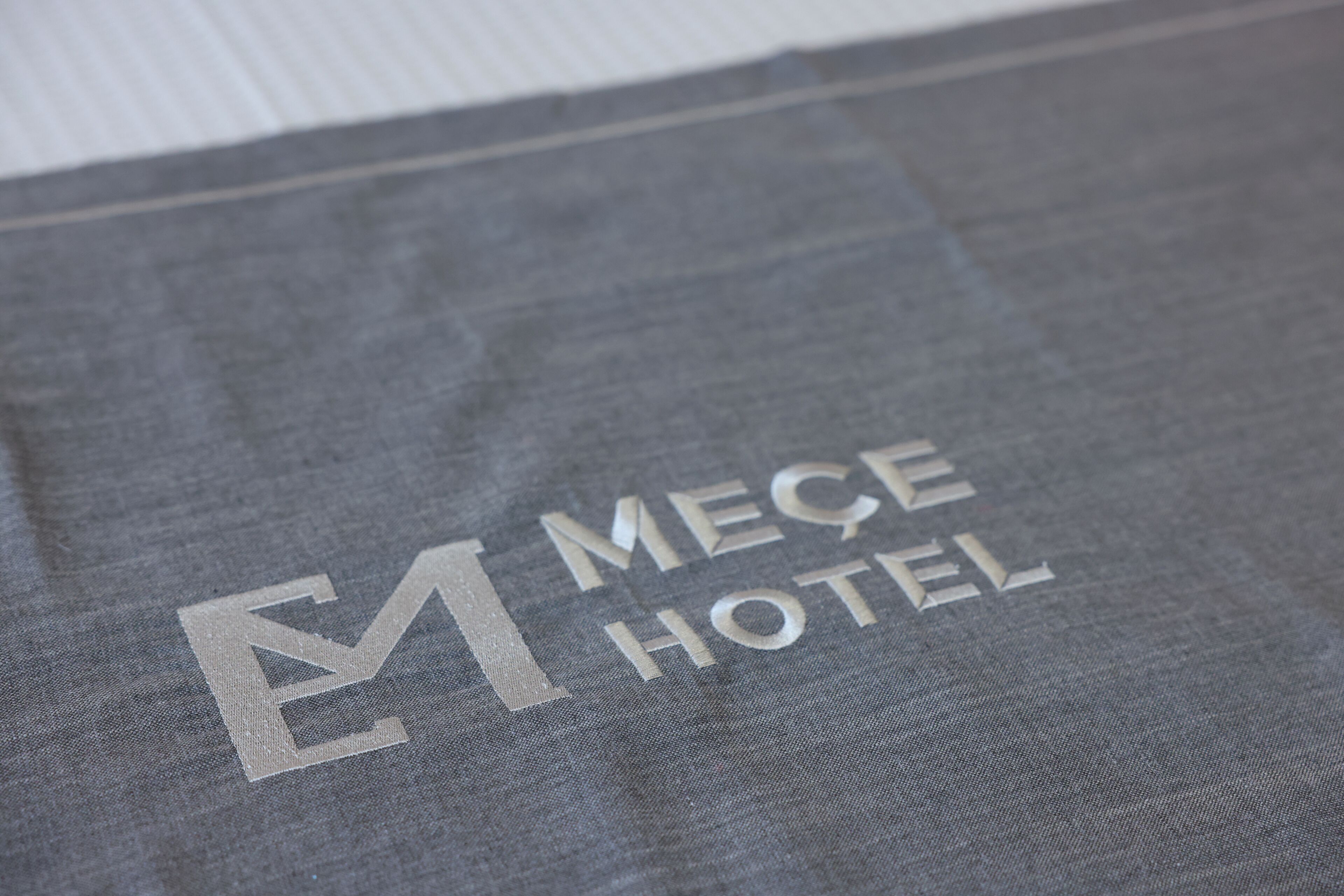A grey fabric with the text "MEÇE HOTEL" printed on it.