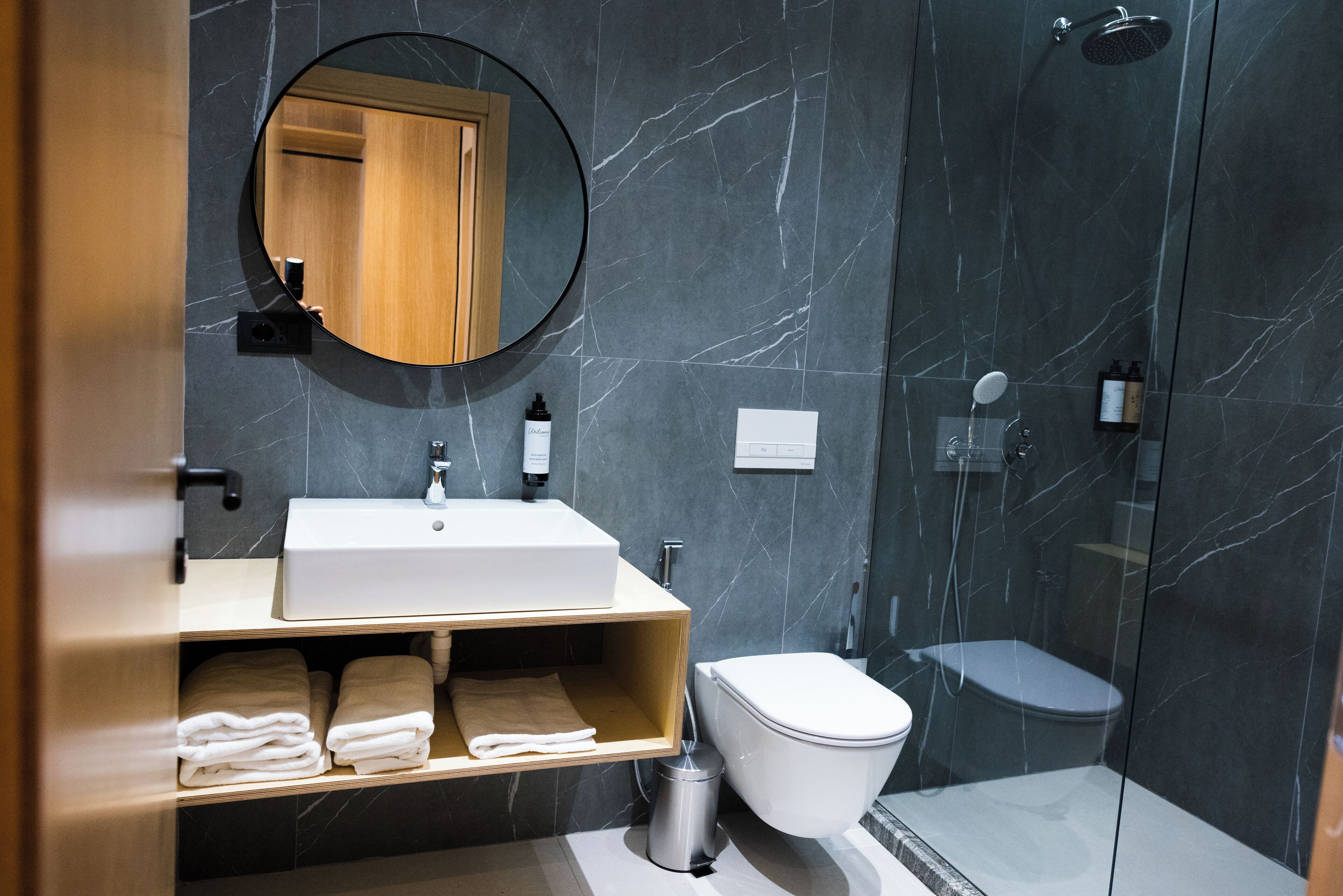 Ein modernes Badezimmer mit Marmorwand, Waschbecken, Toilette und Dusche.