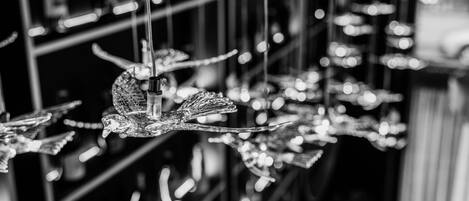 A black and white photo of hanging decorative glass ornaments, including birds and leaves, in a store setting.