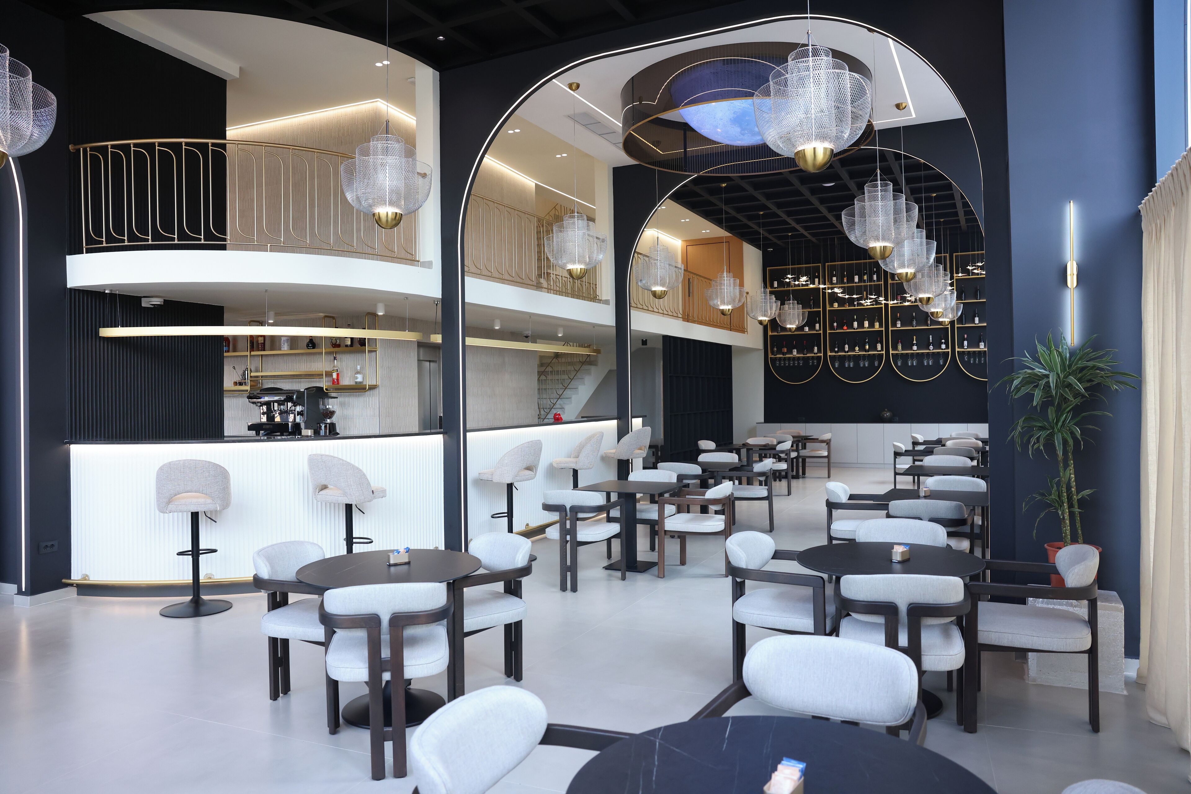 Un intérieur moderne avec un bar central, de nombreux espaces de détente et des luminaires décoratifs.