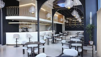 Een modern interieur met een centraal gelegen bar, diverse zithoeken en decoratieve verlichtingsarmaturen.