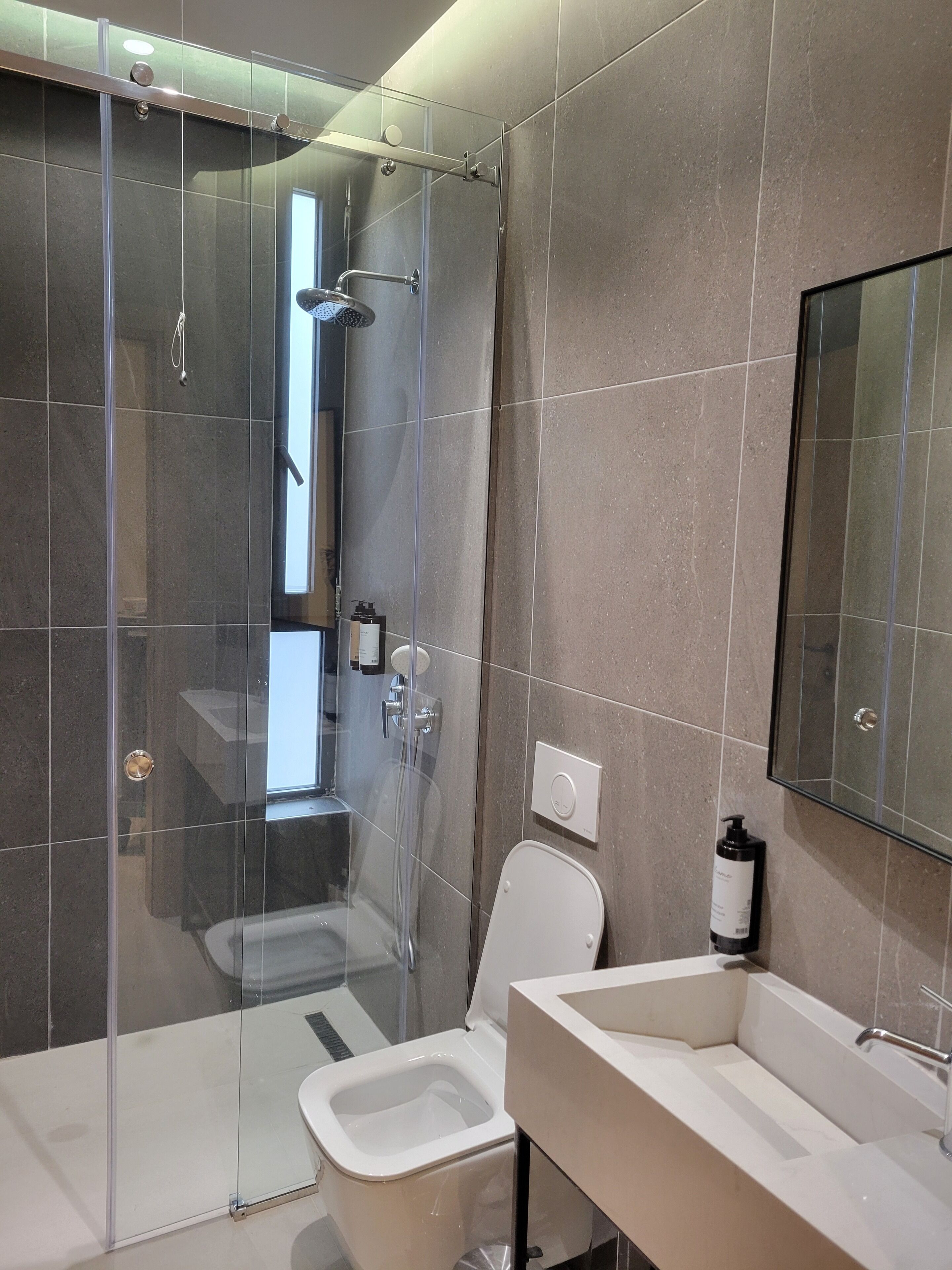 Ein modernes Badezimmer mit Duschkabine, Toilette und Waschbecken mit Spiegel darüber.