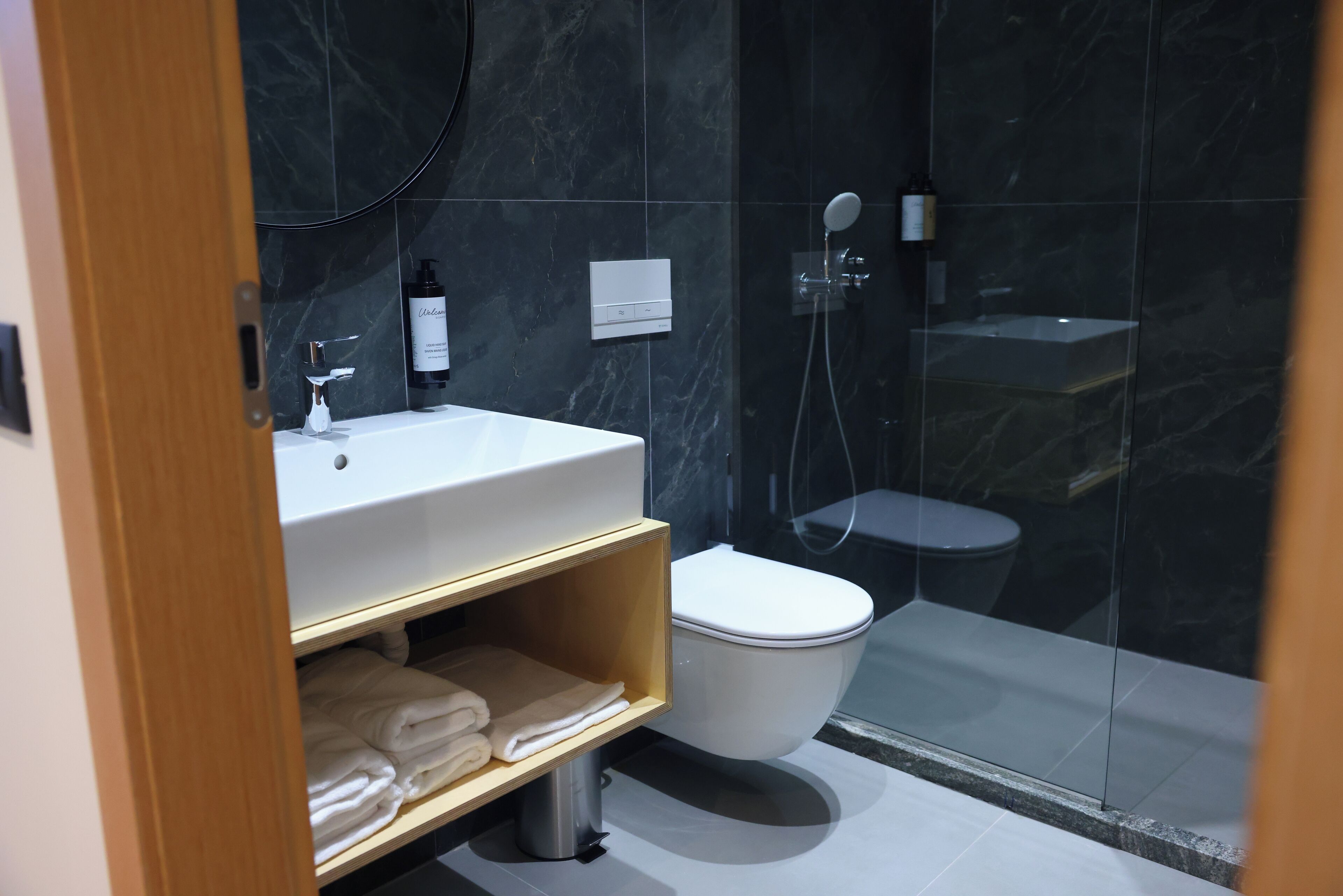 A modern bathroom with a white sink, a toilet, and a glass-enclosed shower area.