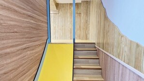 Una scala in legno con una rampa gialla che porta a una piattaforma.