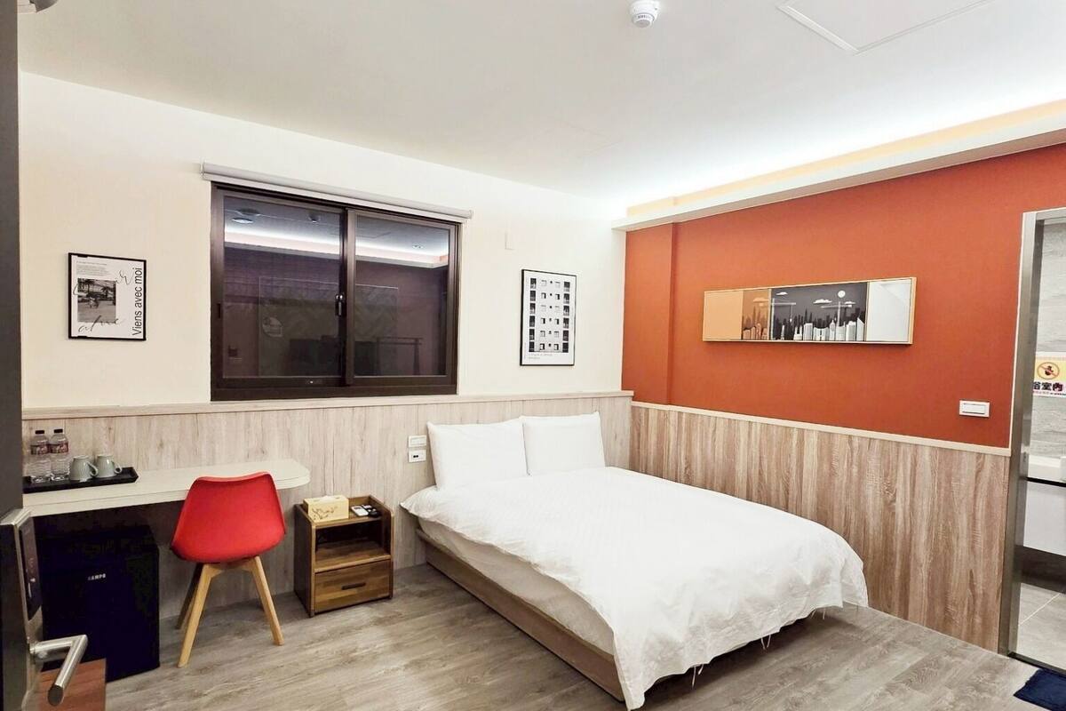 Egy modern hálószoba, amelyben található egy ágy, egy íróasztal, egy szék és egy ablak.