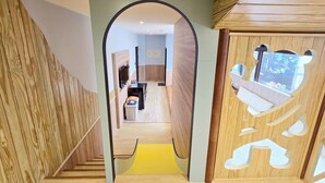 Un interno moderno con una scala in legno, un corridoio che conduce a una stanza con televisore e un pannello a forma di orso in legno.