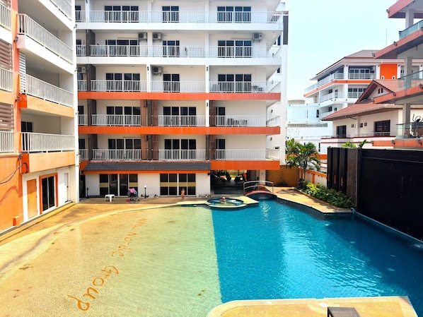 Ein mehrstöckiges Hotel mit Schwimmbad, Balkonen und einem überdachten Bereich.