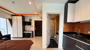 A modern hotel room with a bed, a desk, a shower, and a kitchenette. - Stylish Pool-view Studio With Balcony - New Nordic VIP 3, Pratumnak (Pattaya)