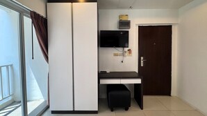 A compact room with a sliding door, a desk with a TV, and a small stool. - Stylish Pool-view Studio With Balcony - New Nordic VIP 3, Pratumnak (Pattaya)