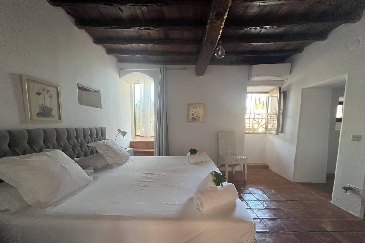 Un dormitorio con una cama grande, una silla y una ventana.