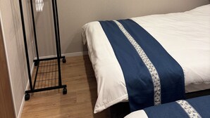Une chambre d’hôtel avec deux lits, un plancher en bois, un tableau accroché au mur et un porte-serviettes en métal noir sur lequel est posée une serviette blanche.
