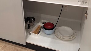 Une cuisine avec un évier, un égouttoir à vaisselle, un saladier rouge et une assiette blanche.