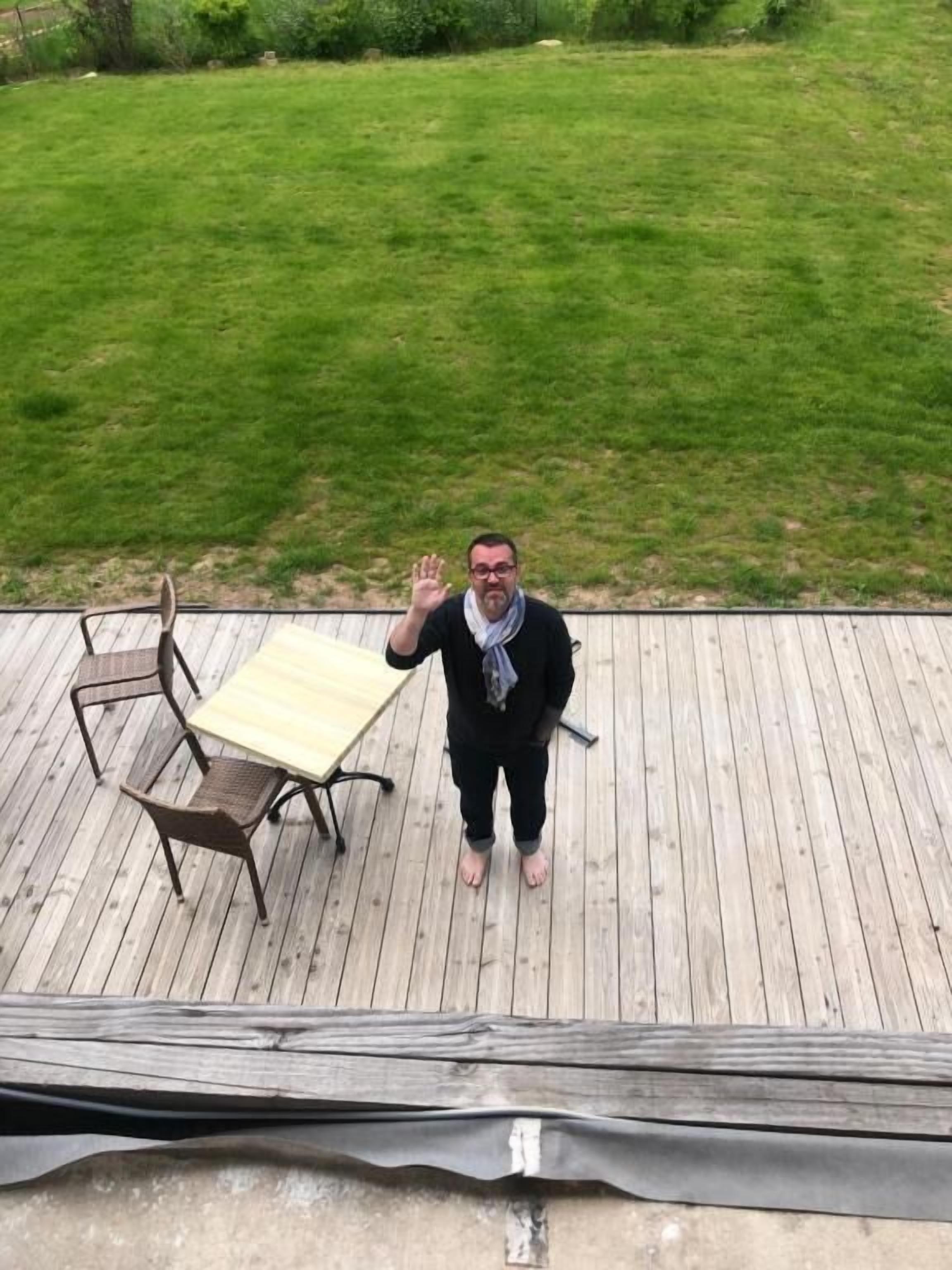 A wooden deck with a table and chairs, surrounded by a grassy lawn.