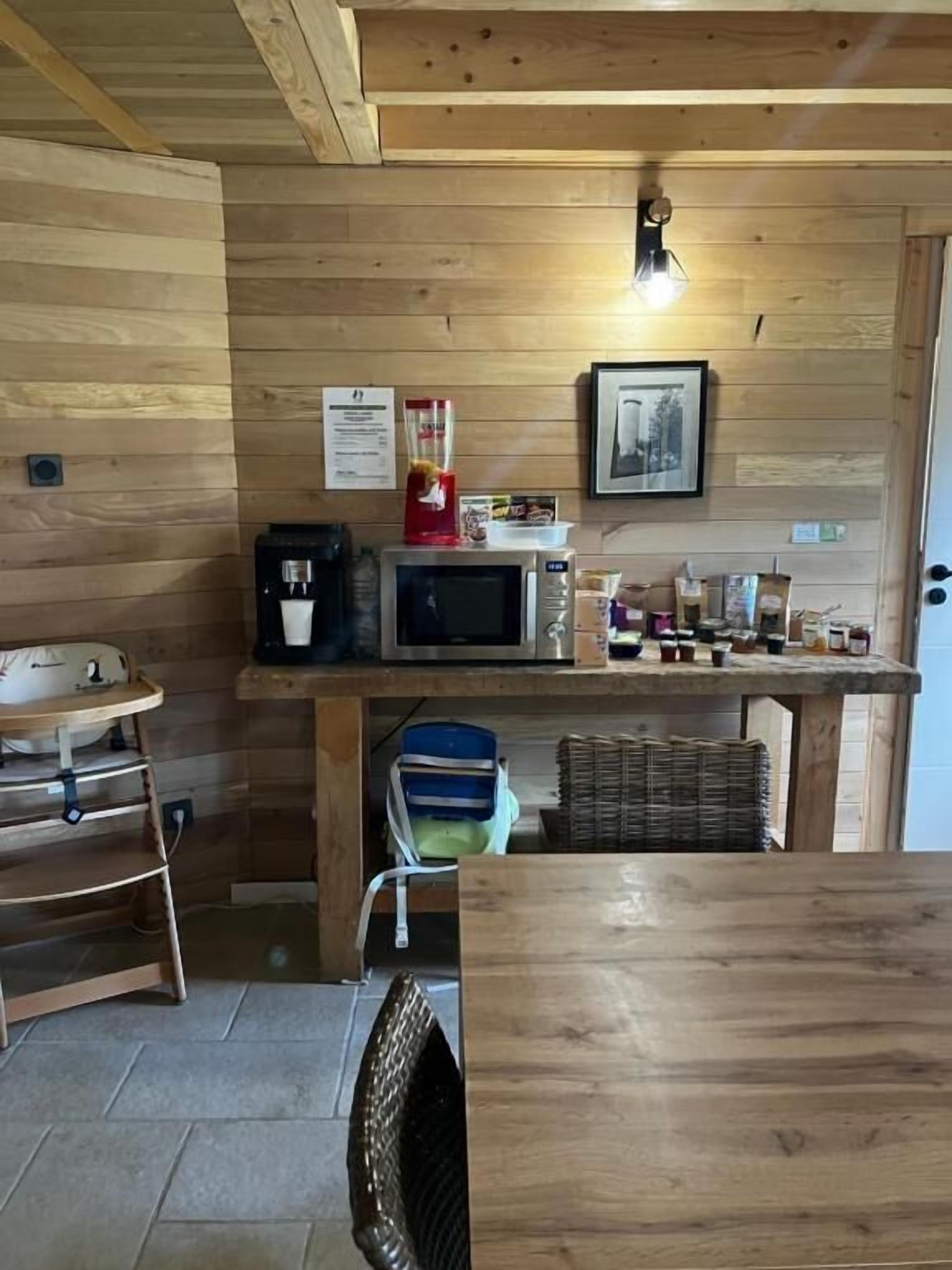 Een compacte keuken met houten wanden, een magnetron, een koffiezetapparaat en diverse etenswaren op het aanrecht.