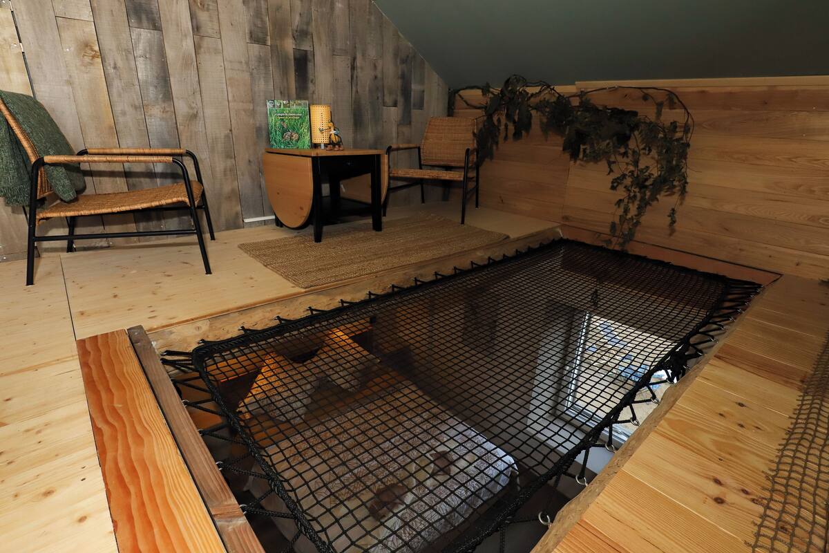 Een kamer met een houten vloer, een kleine houten tafel met een stoel, een bank en een hottub met net.