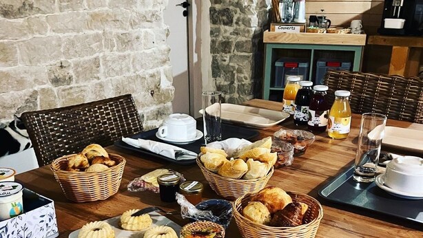 Un buffet de petit-déjeuner proposant un assortiment de viennoiseries, de confitures, de miel et une machine à café.