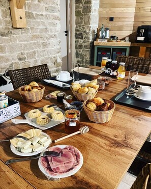 A breakfast buffet with various pastries, jams, honey, and a coffee machine.